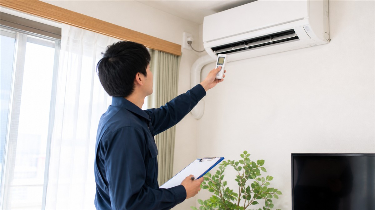 民泊物件でエアコンの吹き出し温度を確認する作業スタッフ